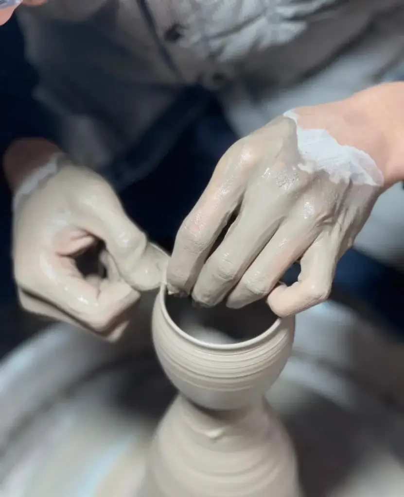 Chinese artisan shaping handmade Chinese porcelain teacup on potter’s wheel